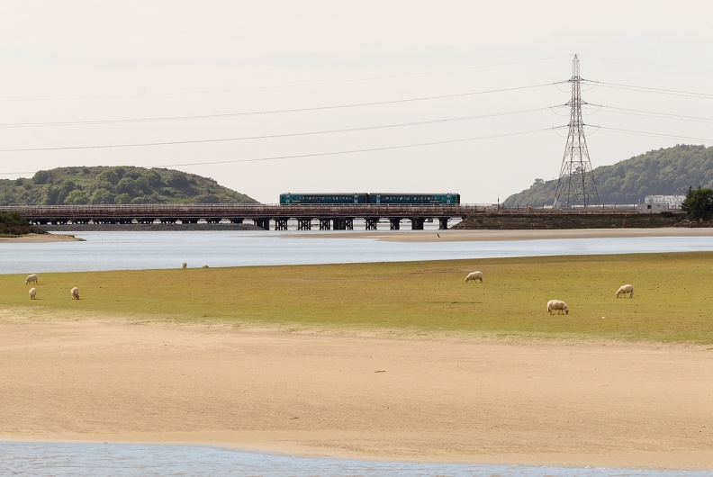 An UID Class 158 crosses the new Pont Briwet with the old timber trestle bridge visible in the foreground. The faulty pylon can be seen on the right. Though it was a replacement for a pylon which had started to list, this replacement is now having to be removed and replaced by a third structure. flickr-welsh snapper-14920692819.jpg